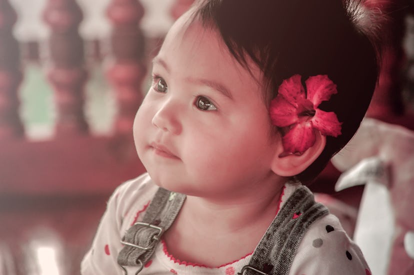 Portrait of a cute little baby girl with flower over ear, vinatge filtered tone 