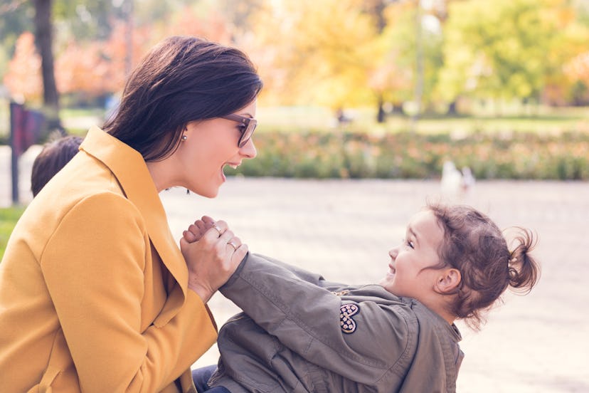 Happy mother with daughter talking and having fun in autumn park.