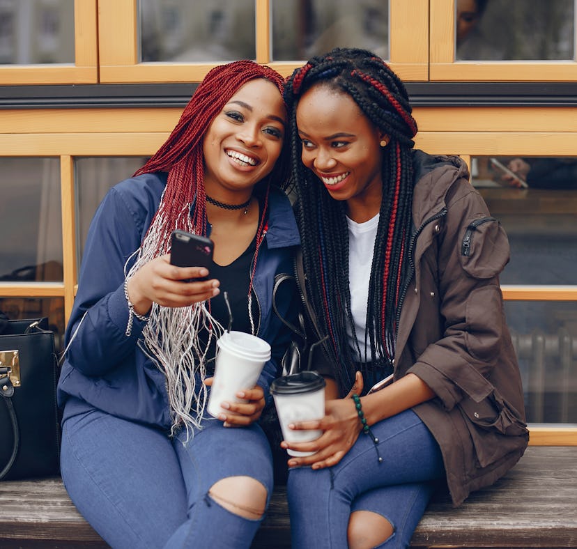 2 sisters with long hair sitting with coffee, wondering what to comment on their sister pics on Inst...