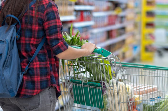 Closeup Young Asian women Hand holding the trolley for shopping over the store blurred in department...