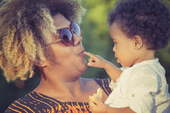 African american mother with her mixed race daughter laughing in the park, enjoying a beautiful day ...