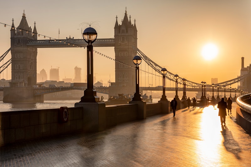 The iconic Tower Bridge in London, UK, during sunrise and silhouettes of people going to their work