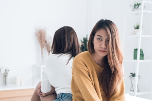 Young Asian lesbian couple argue and turn their back to each other in the period of sad in the bedro...