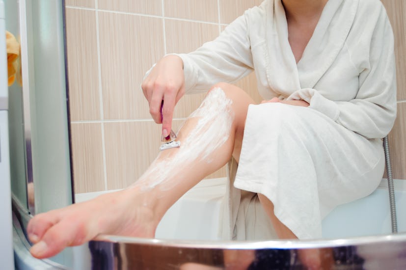 Woman shaves her leg in a story about the benefits of not shaving your pubic hair.