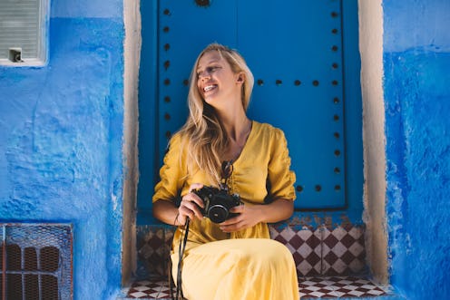 Excited female tourist with retro equipment in hands resting near oriental blue doors in Morocco and...