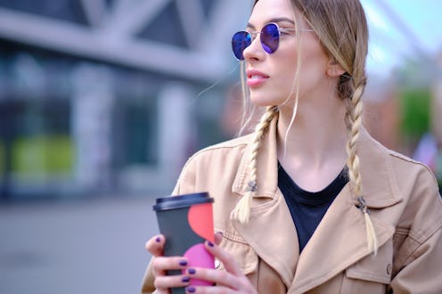 woman walking in the summer city street and drinking take away coffee in paper cup. Breakfast on the...