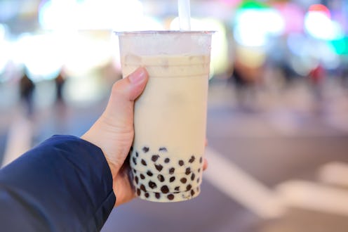 Hand holding a plastic glass of Taiwan iced bubble milk tea with Blur background, bokeh background