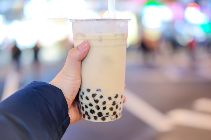 Hand holding a plastic glass of Taiwan iced bubble milk tea with Blur background,  bokeh background 
