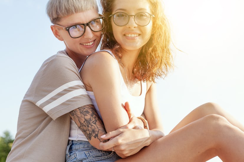 Beautiful young lesbian couple gently hugging in the sunshine, homosexual family, love and tolerance