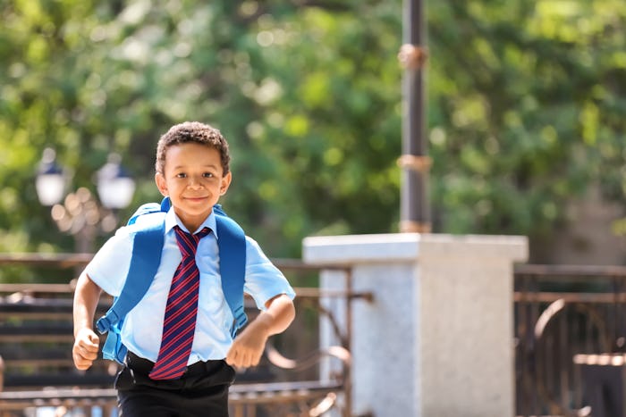 Cute African-American schoolboy running outdoors