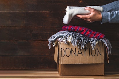 Donation concept. Donation box with donation clothes on a wooden background. Charity. Helping poor a...