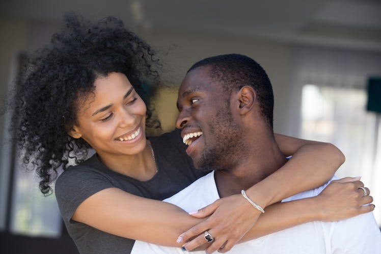 Portrait of happy black husband and wife embrace looking at each other, smiling African American cou...