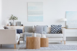 Two wooden coffee tables with plant in pot in front of grey corner sofa in fashionable living room i...