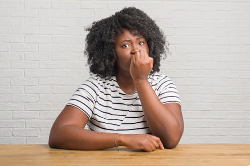 Young african american woman sitting on the table at home looking stressed and nervous with hands on...