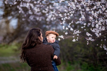 Little baby boy with her young mother in the blossom garden. Spring