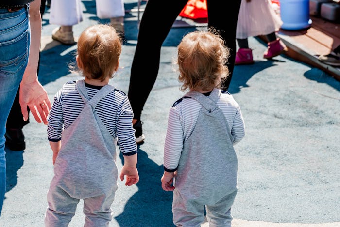 Little twin babies are walking on the street