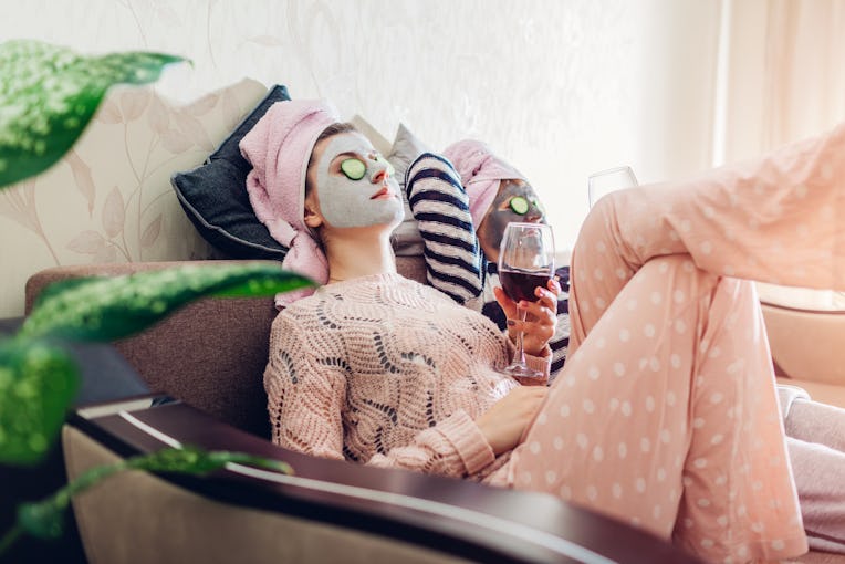 Mother and her adult daughter applied facial masks and cucumbers on eyes. Women chilling while havin...