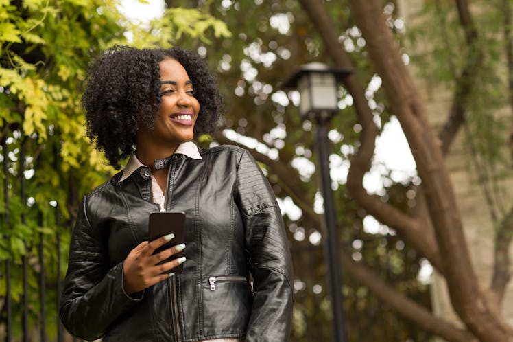 African American woman walking and texting outside.