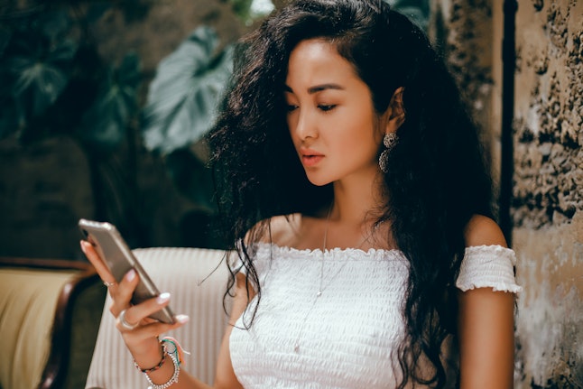 Close-up of female hands holding mobile phone with copy space blank, scree for your text message advertising or promotional content, hipster girl watching video on cell phone during coffee break