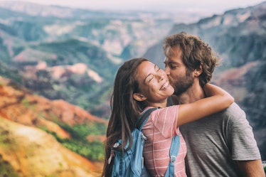 Couple in love kissing on nature travel hiking in Hawaii mountains. Young hikers people happy togeth...