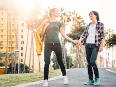 Happy lesbian couple having fun dating outdoor - Young gay women walking and holding hands outside -...