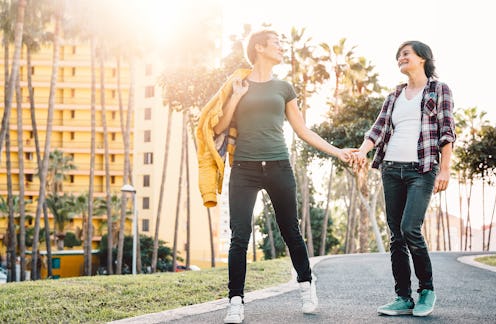 Happy lesbian couple having fun dating outdoor - Young gay women walking and holding hands outside -...