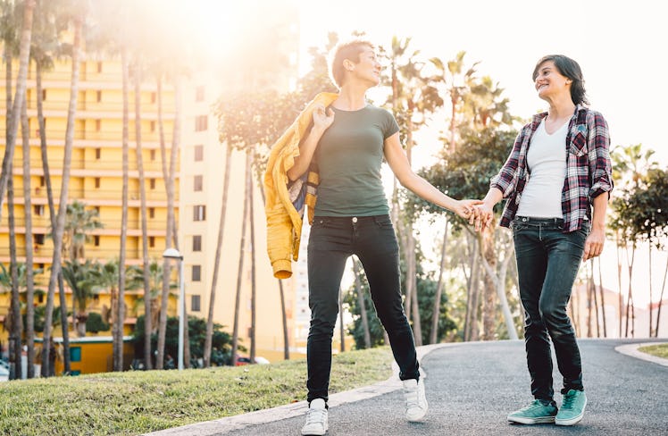 Happy lesbian couple having fun dating outdoor - Young gay women walking and holding hands outside -...