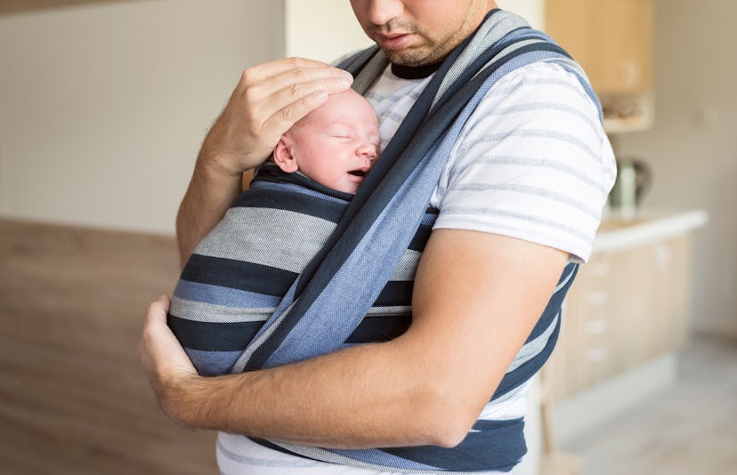 Unrecognizable young father with his son in sling