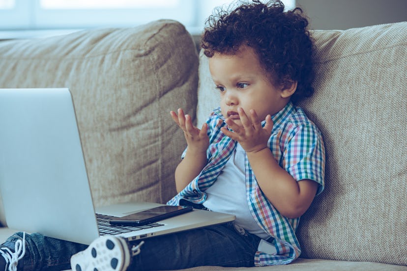 How does this thing turns on? Little African baby boy looking confused while sitting on the couch at...