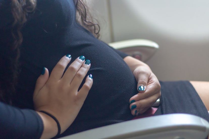 Pregnant woman in airplane chair. Belly of pregnant.