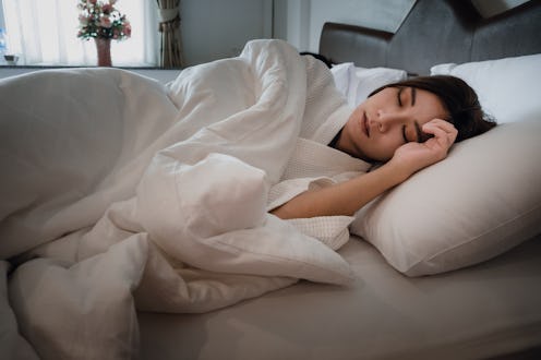 Asian teen girl lying on bed in room.Young woman sleeping on white pillow in bed