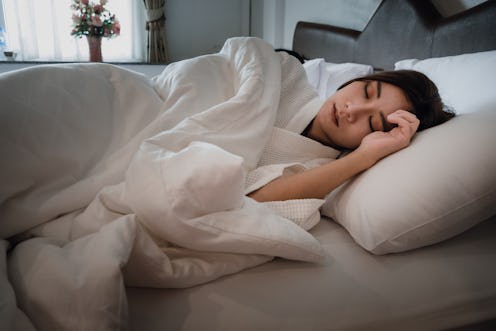 Asian teen girl lying on bed in room.Young woman sleeping on white pillow in bed