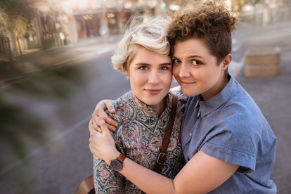 Portrait of an affectionate young lesbian couple hugging each other while standing together on a cit...