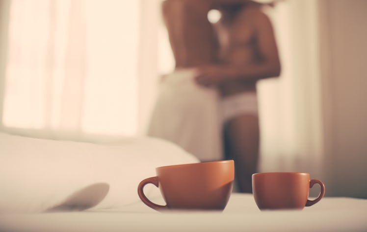 Luxury bedroom with cup of coffee. Two cups of coffee in morning. Passionate couple kissing, boy and...