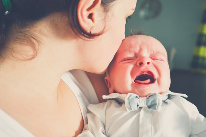 Mother holding crying baby. Young woman with her little son.