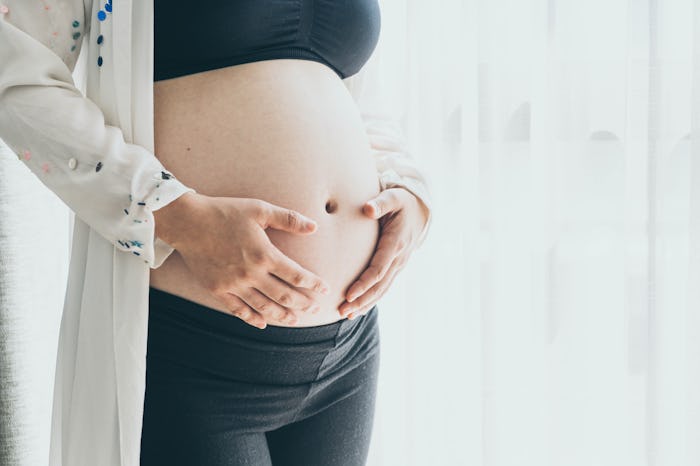 Belly of pregnant woman with hands - selective focus point with vintage filter style