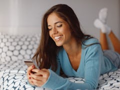 Young woman texting from the bed