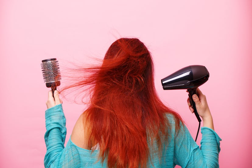 Woman holding a hairdryer on a pink background