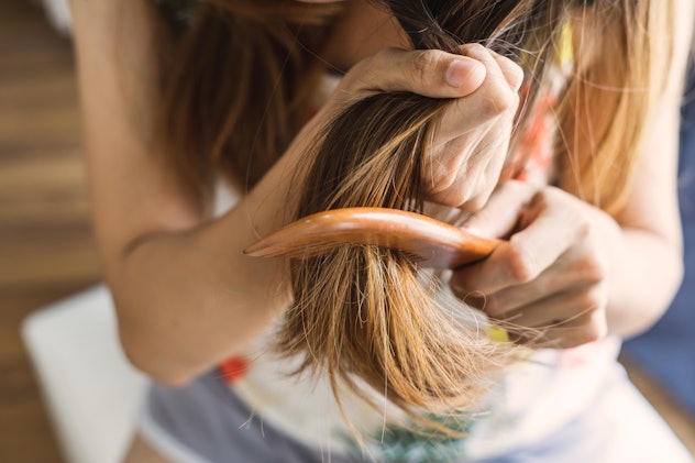 Woman combing tangled hair, Hair problems concept