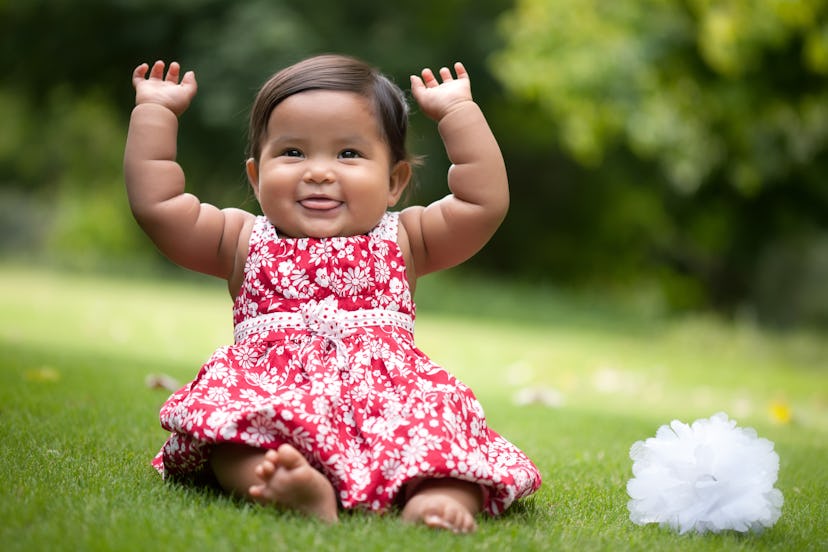 cute baby girl gesturing with her arms up and blowing raspberries