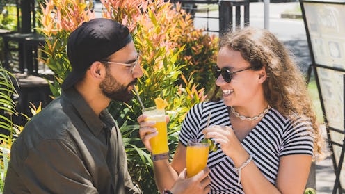 Beautiful woman giving her boyfriend drink while happily laughing – Young couple having fun on a dat...