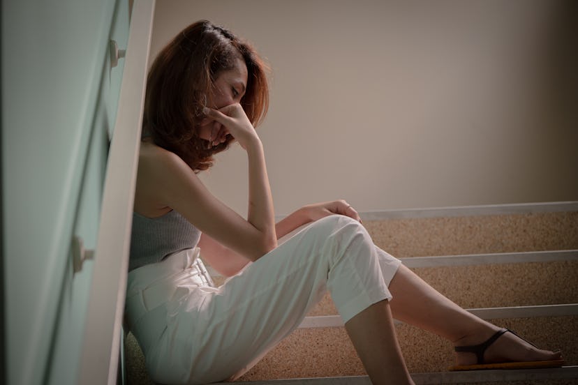 Sad Lonely (Alone) Woman sitting down on the building stairs against the wall concept of unhappiness...