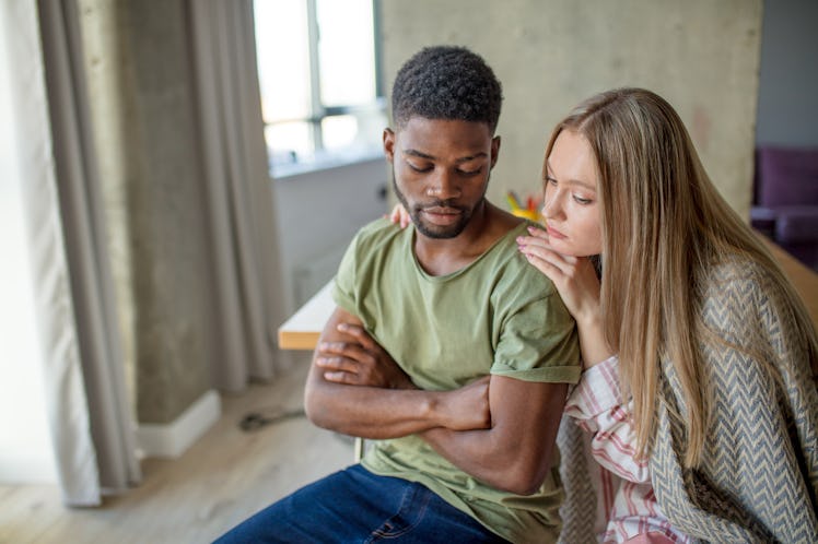 Caucasian blonde woman consoles and supports her african hipster boyfriend, who is having gloomy and...