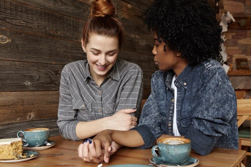 A couple holds hands while sitting at a table with their lattes at a café.