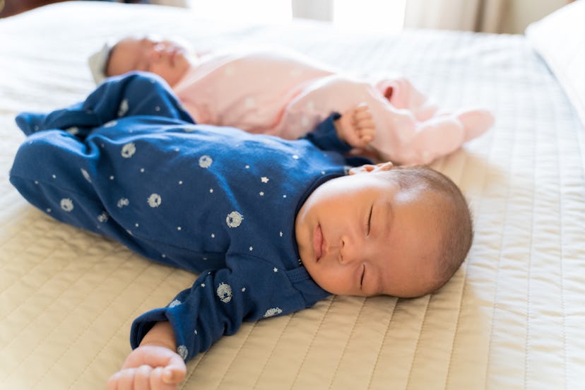 Cute twin babies sleeping peacefully on bed in bedroom