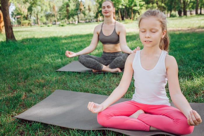 Small girl is sitting in front while woman is sitting on the back. They are meditating. Young women ...