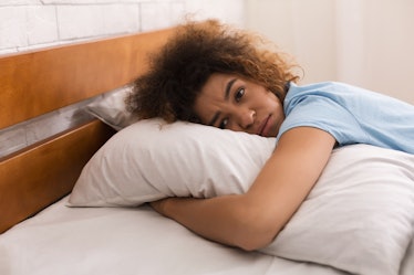 Worried girl hugging pillow and having depressing thoughts, lying in bed