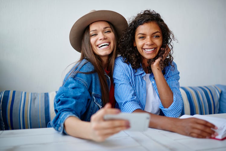 Portrait for cheerful multiracial women posing for common selfie on smartphone during friendly meeti...