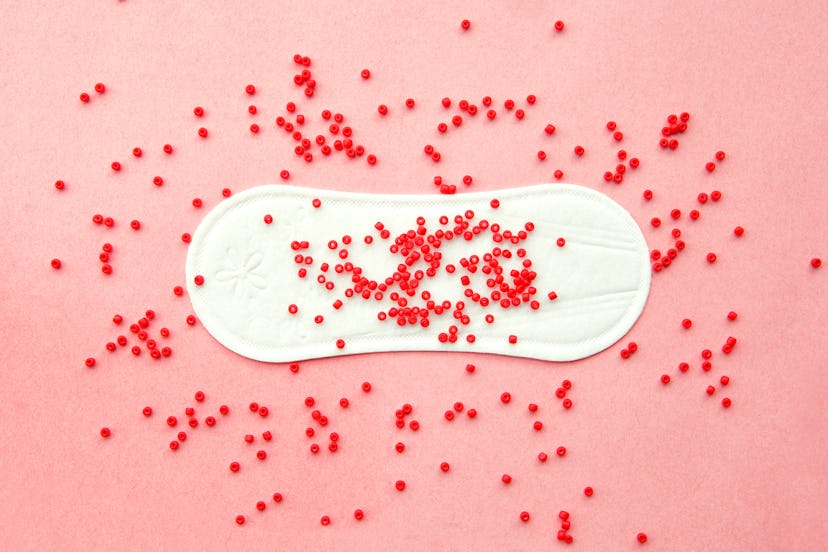 menstruation pad with red beads as blood drops all over the pink background, women critical days, gy...