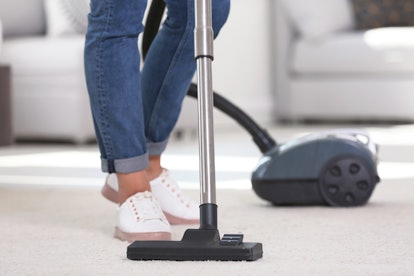 Woman cleaning carpet with vacuum cleaner, closeup